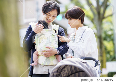 生後三ヶ月の赤ちゃんと散歩する父母の写真素材