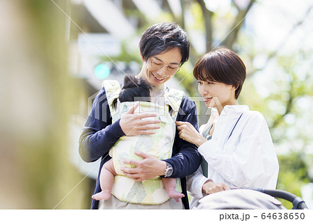 生後三ヶ月の赤ちゃんと散歩する父母の写真素材