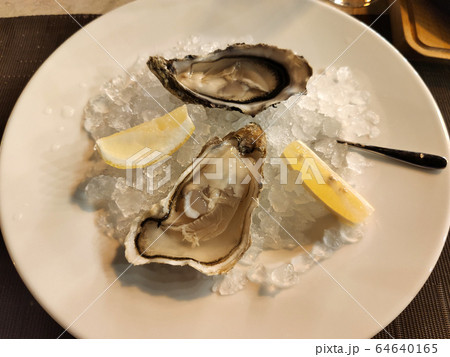 Fresh Oysters with lime on a large plate with ice. Fresh Oysters with lime on a large plate with ice. 64640165