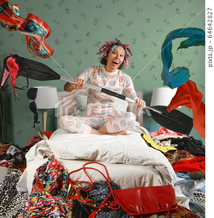 Woman sitting on a bed paddles as if in a boat 64642827