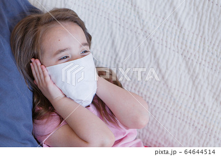 Portrait of a child who covered her face with a mask. A girl is home-schooled. The concept of quarantine, self-isolation, protection from coronavirus, virus, fear of disease, treatment, medicine 64644514