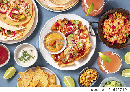 Mexican food, a flat lay. Nachos, tortillas, Paloma cocktails and other dishes, shot from the top 64645710