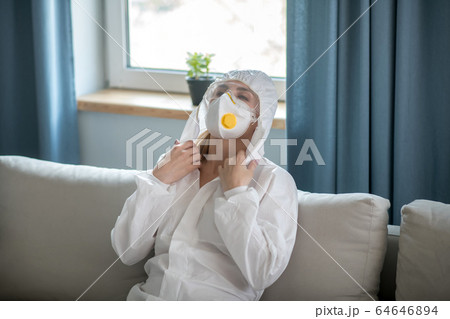 Woman in white workwear and respirator feeling tired 64646894
