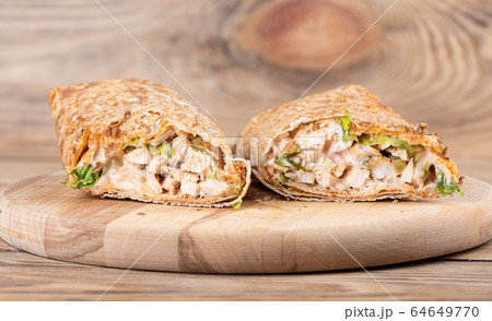 Shawarma Middle Eastern dish of pita bread, stuffed with grilled and then minced chicken meat. 64649770