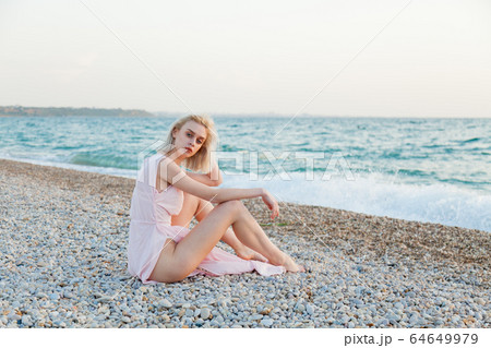 Portrait of a beautiful fashionable blonde woman on an empty beach by the sea Portrait of a beautiful fashionable blonde woman on an empty beach by the sea 64649979