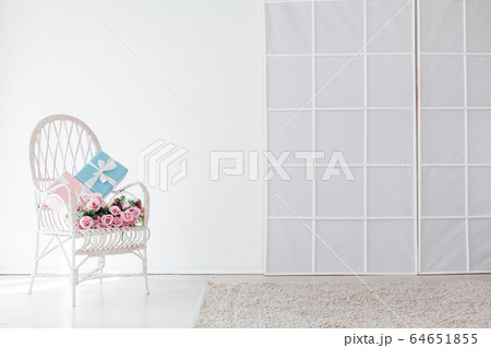 white vintage chair with gift and flowers in the interior of the white room white vintage chair with gift and flowers in the interior of the white room 64651855