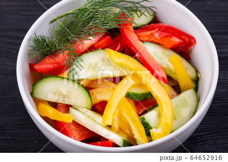 Salad of fresh cucumbers, tomatoes and Bulgarian pepper with greens 64652916