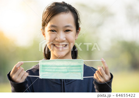 Asian child girl show a medical protective mask,campaigning to wear a mask before leaving the house to prevent the infection of the Coronavirus epidemic or outbreak of Covid-19,flu,contagious disease 64655422