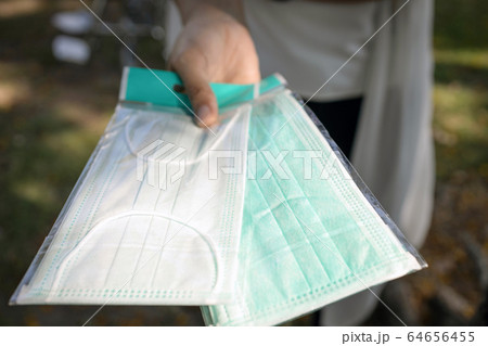 Hand of woman with face mask for Covid-19 protection,generous girl sharing medical mask and raised her hand up,giving hygienic mask to prevent Coronavirus pandemic,spreading contagious disease,flu 64656455