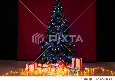 Christmas tree garland lights with new year's gifts red background 64657634