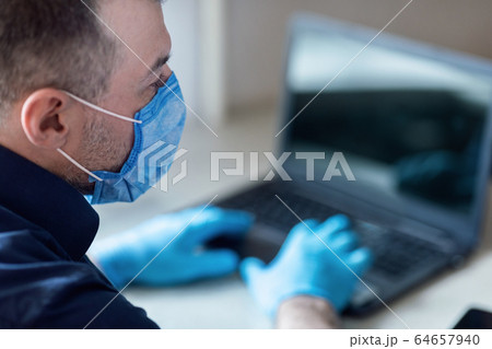 Businessman Sitting At Laptop Working From Home Wearing Medical Mask Businessman Sitting At Laptop Working From Home Wearing Medical Mask 64657940