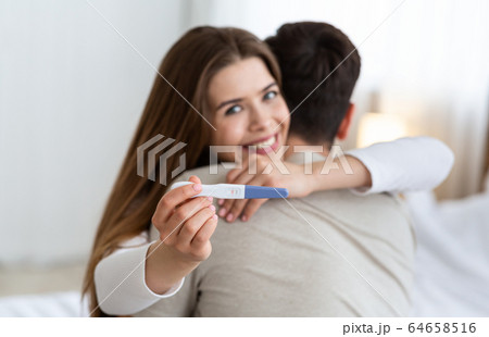 Focus on pregnancy test. Young husband and wife hugging 64658516