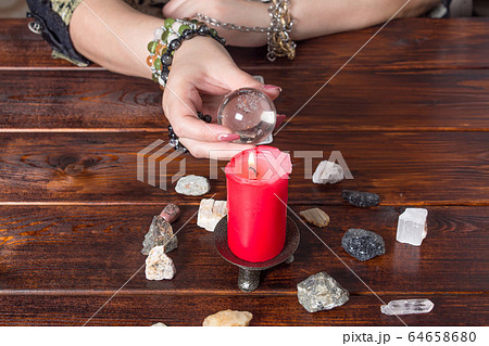 Fortune teller predicts fate using a magic ball, stones and a lit candle.A Gypsy telling fortunes by the hand.Christmas fortune telling and fortune telling.Spiritism and magic sessions.Psychic at work Fortune teller predicts fate using a magic ball, stones and a lit candle.A Gypsy telling fortunes by the hand.Christmas fortune telling and fortune telling.Spiritism and magic sessions.Psychic at work 64658680