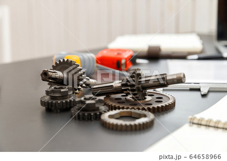 Gear with machine part on engineer desk. 64658966