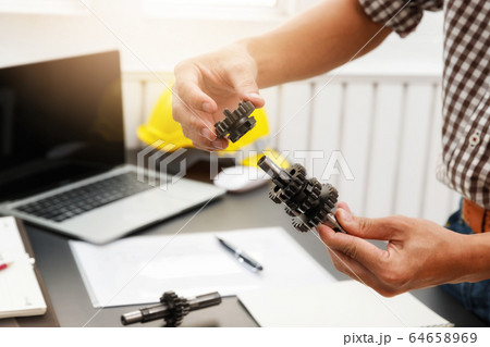 Engineers try to assemble machine parts together. 64658969