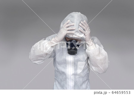 伝染病の拡大に頭を抱える防護服の男性 新型ウィルス パンデミック 医療崩壊 疲労イメージの写真素材