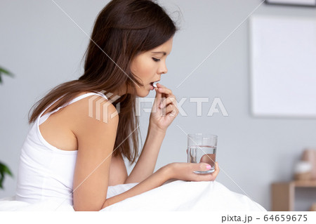 Millennial woman taking painkiller medicine to relieve headache 64659675