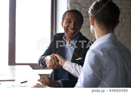 Satisfied black client shaking hands thanking manager for good d Satisfied black client shaking hands thanking manager for good d 64660490