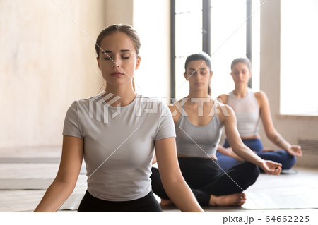 Beautiful girls meditating sitting in lotus position Beautiful girls meditating sitting in lotus position 64662225