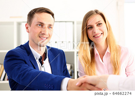 Smiling man and woman shake hands as hello in office Smiling man and woman shake hands as hello in office 64662274