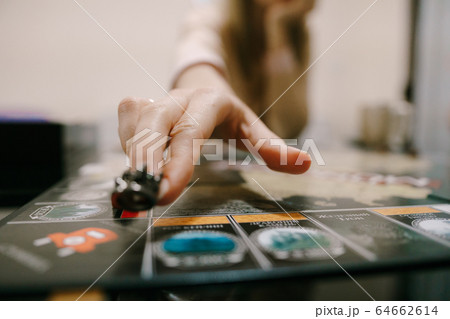 Woman's hand moves figurine in board game, close-up. Home board games Woman's hand moves figurine in board game, close-up. Home board games 64662614