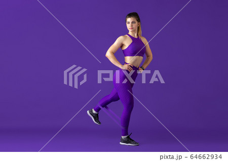 Beautiful young female athlete practicing on purple studio background, monochrome portrait Beautiful young female athlete practicing on purple studio background, monochrome portrait 64662934