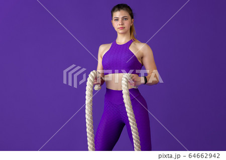 Beautiful young female athlete practicing on purple studio background, monochrome portrait Beautiful young female athlete practicing on purple studio background, monochrome portrait 64662942