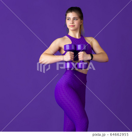 Beautiful young female athlete practicing on purple studio background, monochrome portrait Beautiful young female athlete practicing on purple studio background, monochrome portrait 64662955
