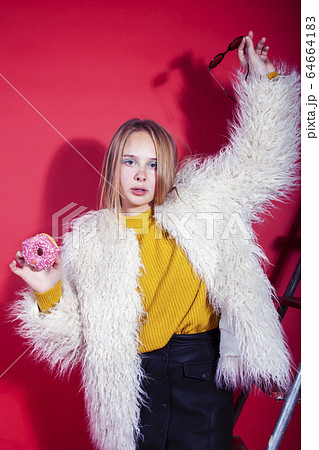 young pretty fashion teenage girl on bright red background holding donut, happy smiling lifestyle people concept 64664183