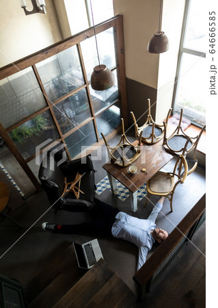 Public institutions closed due to COVID-19 or Coronavirus outbreak lockdown, stressed owner of small business alone lying down the floor in his cafe, restaurant, bar 64666585