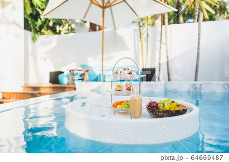 Breakfast and afternoon tea set floating around swimming pool 64669487