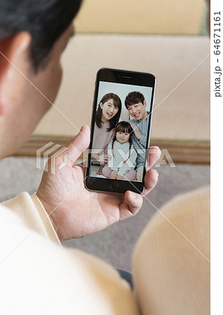 スマホで孫とビデオチャットする祖父母夫妻　　オンライン帰省　イメージ 64671161