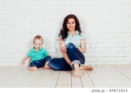 mom and young boy son sit on the floor brick wall mom and young boy son sit on the floor brick wall 64671814