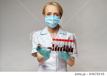 medical doctor nurse woman wearing protective mask and gloves - holding rack with virus blood tests medical doctor nurse woman wearing protective mask and gloves - holding rack with virus blood tests 64678549