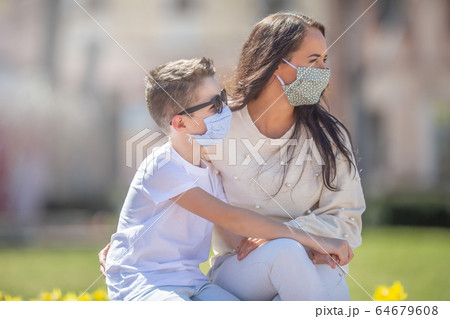 Mother and son with face masks on their faces both 64679608