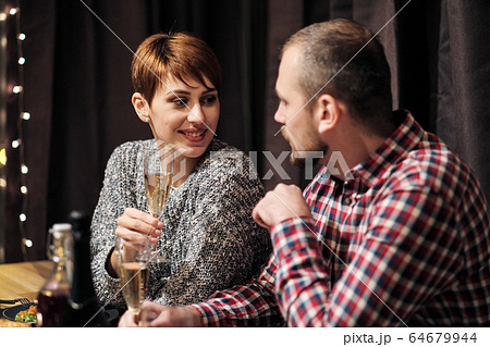 Friends holiday party dinner at home around the table. Celebrate Christmas. People eat, drink champagne, talk and laugh. Friends holiday party dinner at home around the table. Celebrate Christmas. People eat, drink champagne, talk and laugh. 64679944