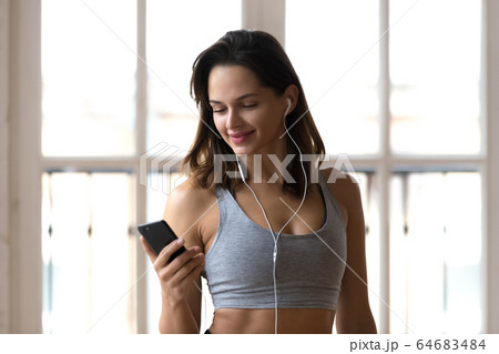 Positive sporty girl using smartphone listening music during wor Positive sporty girl using smartphone listening music during wor 64683484