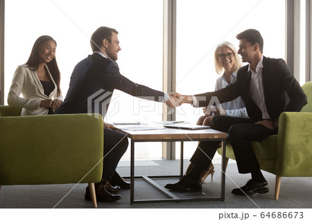 Arabic and caucasian male business partners handshaking at meeting 64686673