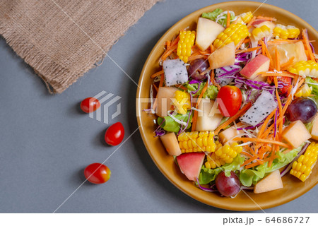 Fruits salad and vegetable in dish plate on gray Fruits salad and vegetable in dish plate on gray 64686727