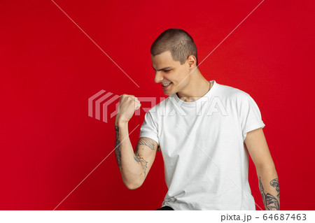 Caucasian young man's portrait on red studio background, emotinal and expressive Caucasian young man's portrait on red studio background, emotinal and expressive 64687463
