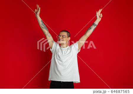 Caucasian young man's portrait on red studio background, emotinal and expressive 64687565