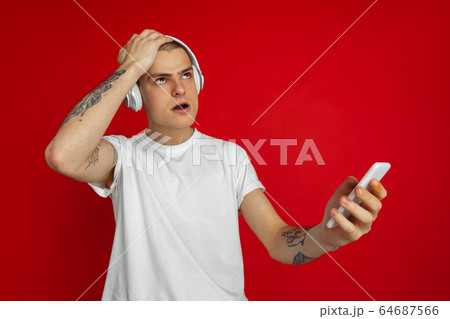 Caucasian young man's portrait on red studio background with copyspace - emotional and expressive, angry and upset 64687566