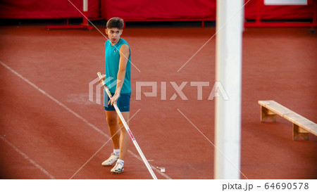 Pole vault training on the stadium - a young man preparing before the jump 64690578