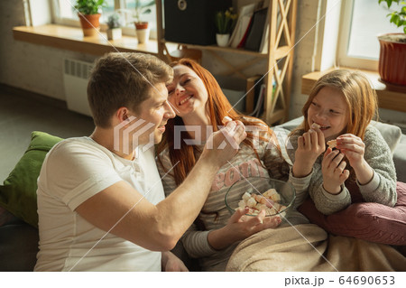 Family spending nice time together at home, looks happy and cheerful, watching TV 64690653