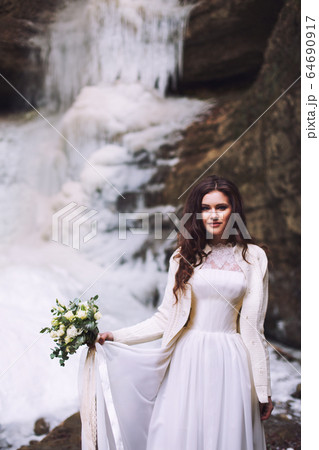 Bride in wedding dress with bouquet in front of glacier Bride in wedding dress with bouquet in front of glacier 64690917