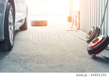 Car wheel repair shop outdoor ground . Seasonal winter tyre change at workshop. Vehicle tire repair, inspection and maintenance. Automotive garage with inflatable pneumatic air jacks. Copyspace text 64691250