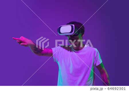 Caucasian man's portrait isolated on purple studio background in neon light Caucasian man's portrait isolated on purple studio background in neon light 64692301