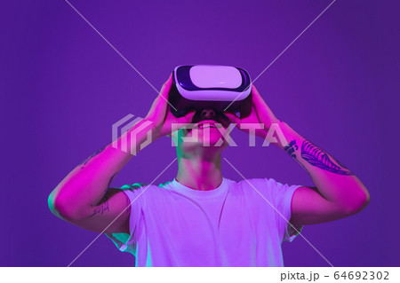 Caucasian man's portrait isolated on purple studio background in neon light Caucasian man's portrait isolated on purple studio background in neon light 64692302