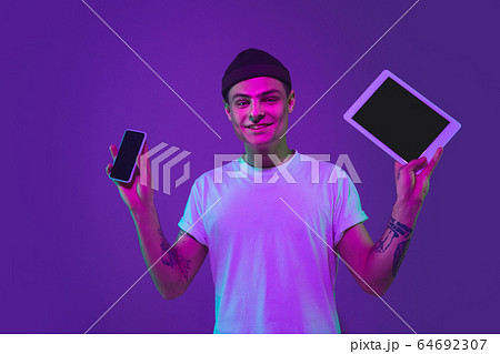 Caucasian man's portrait isolated on purple studio background in neon light 64692307