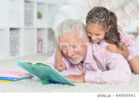 Grandfather reading book with his little granddaughter 64693041